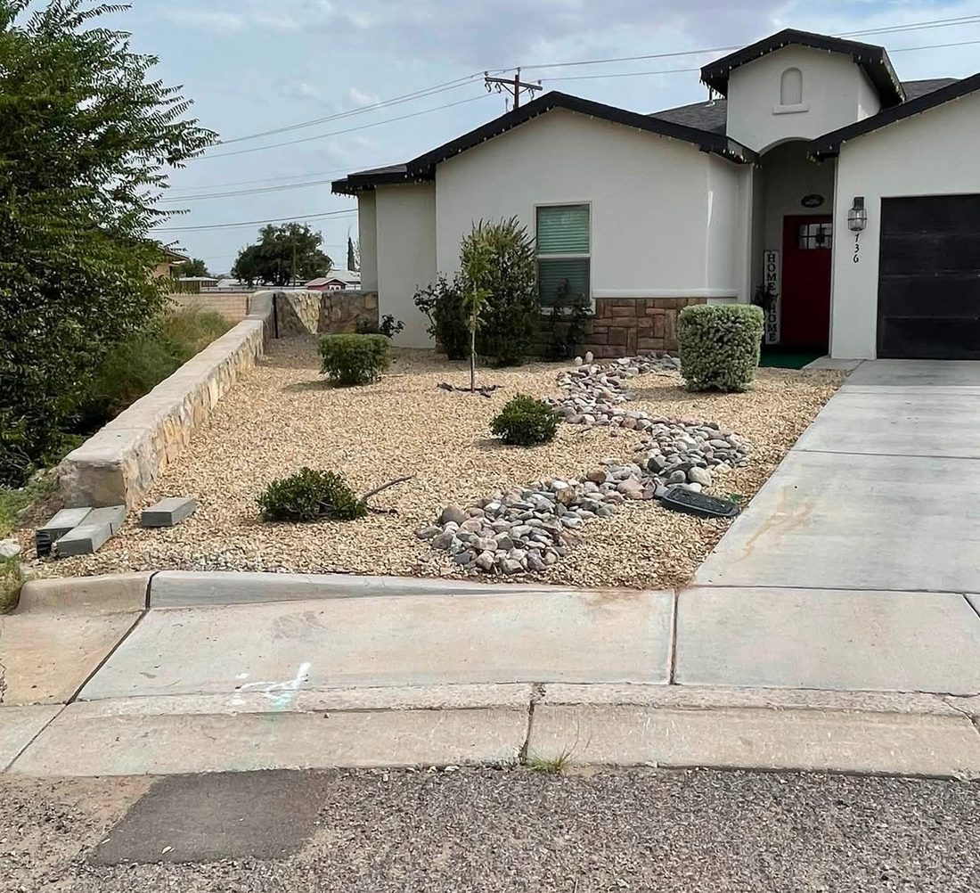 Same front yard rock bed after cleanup, with weeds removed and shrubs tidied.
